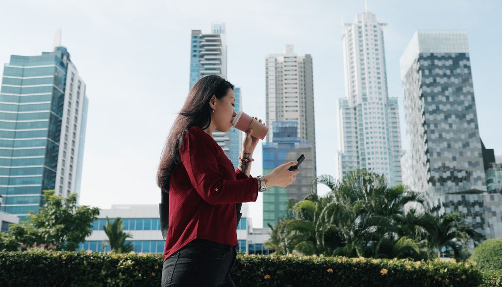chinese-woman-with-phone-walking-and-drinking-coff-5SHYTM8
